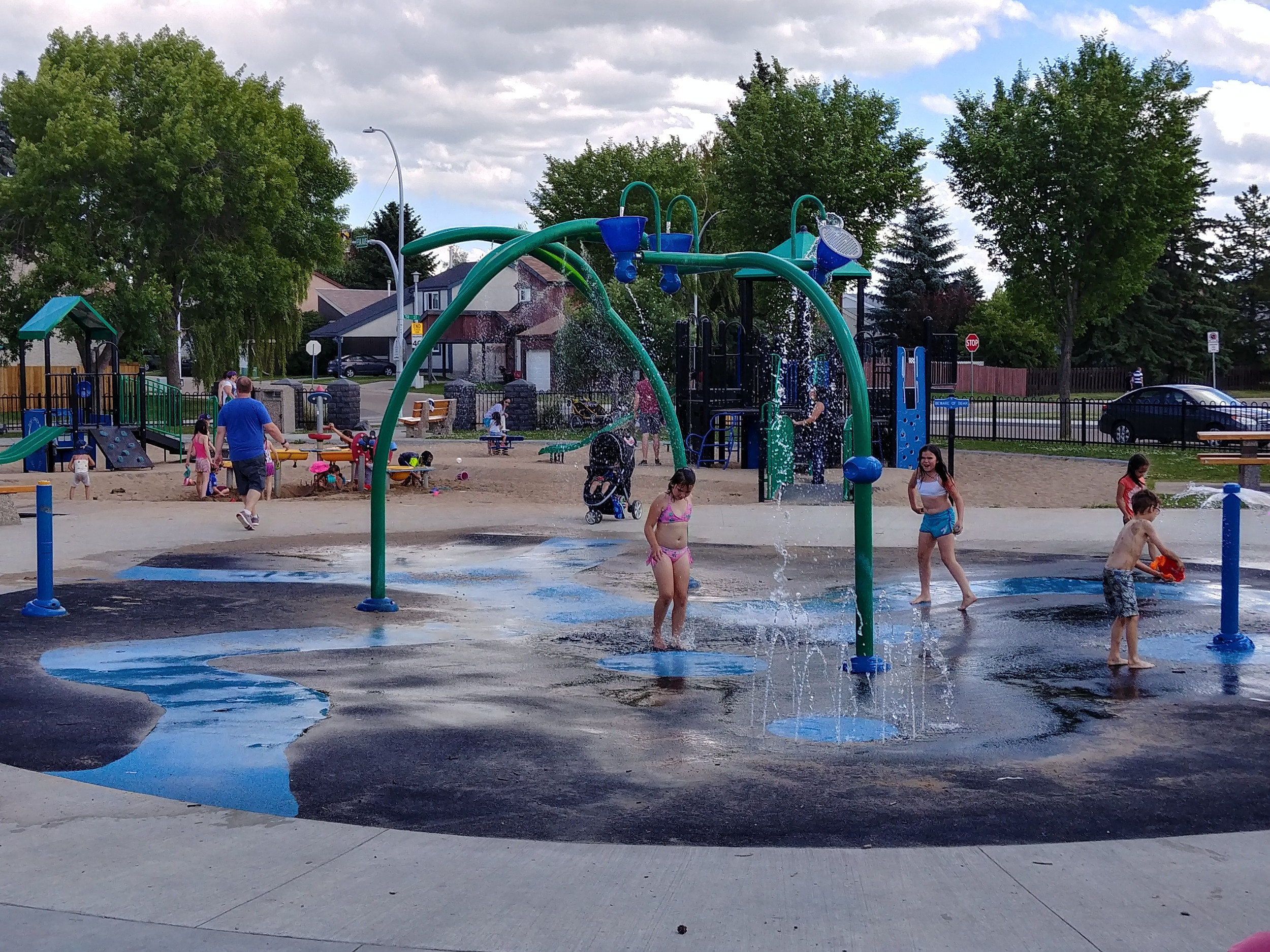 children playing in a spray park beside the community league