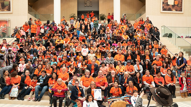 A photo of people gathered on the city steps wearing orange shirts
